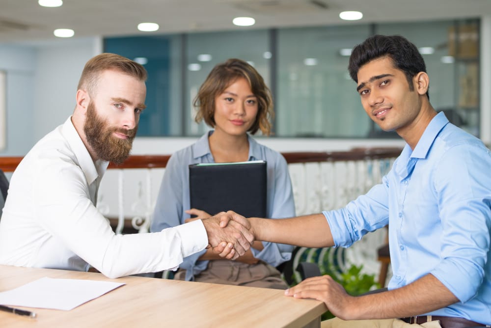 Business executives shaking hands after completing a staffing acquisition
